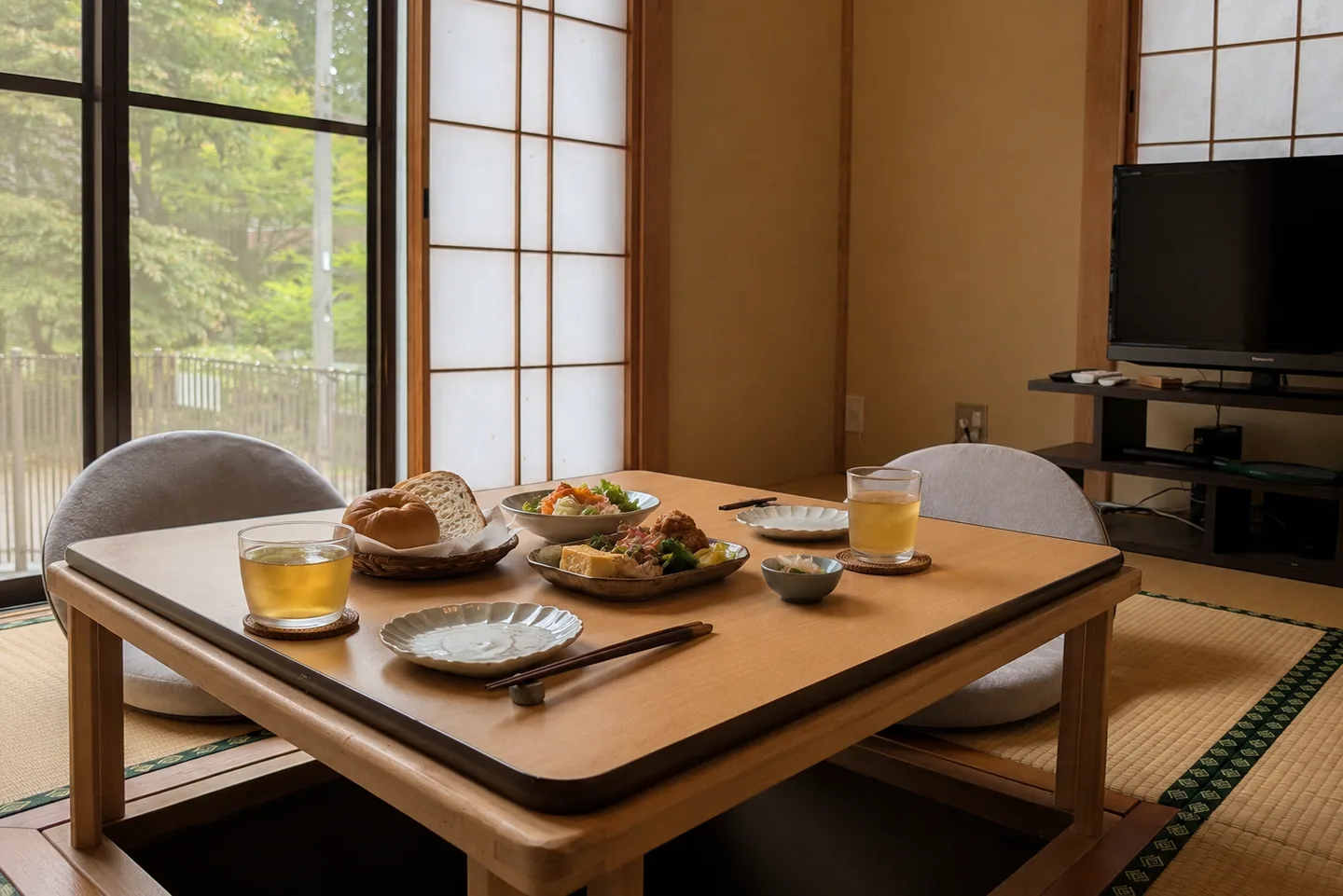 Stay3Villa 一刻の掘りごたつに、2名分の軽い食事と飲み物を並べた様子